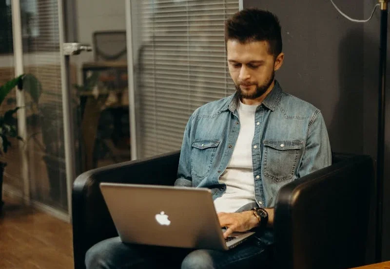 Fotografía que muestra a un hombre diseñando en su laptop mac