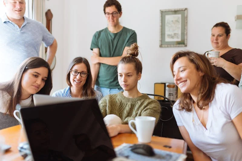 Fotografia de siete estudiantes revisando apuntes en una laptop 