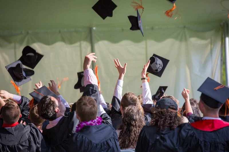 Fotografía de estudiantes graduándose y tirando al aire su birrete 